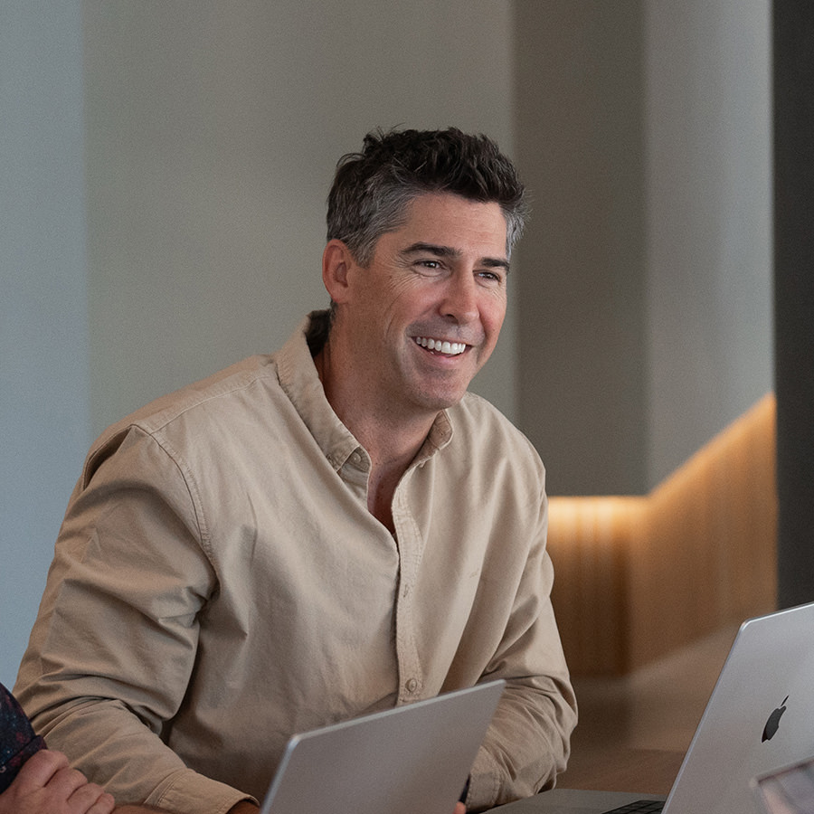 A man smiling while working on a laptop.