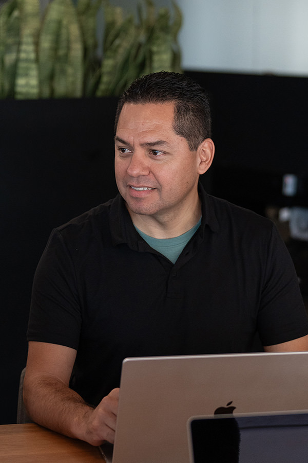 A man smiling and working on a laptop.
