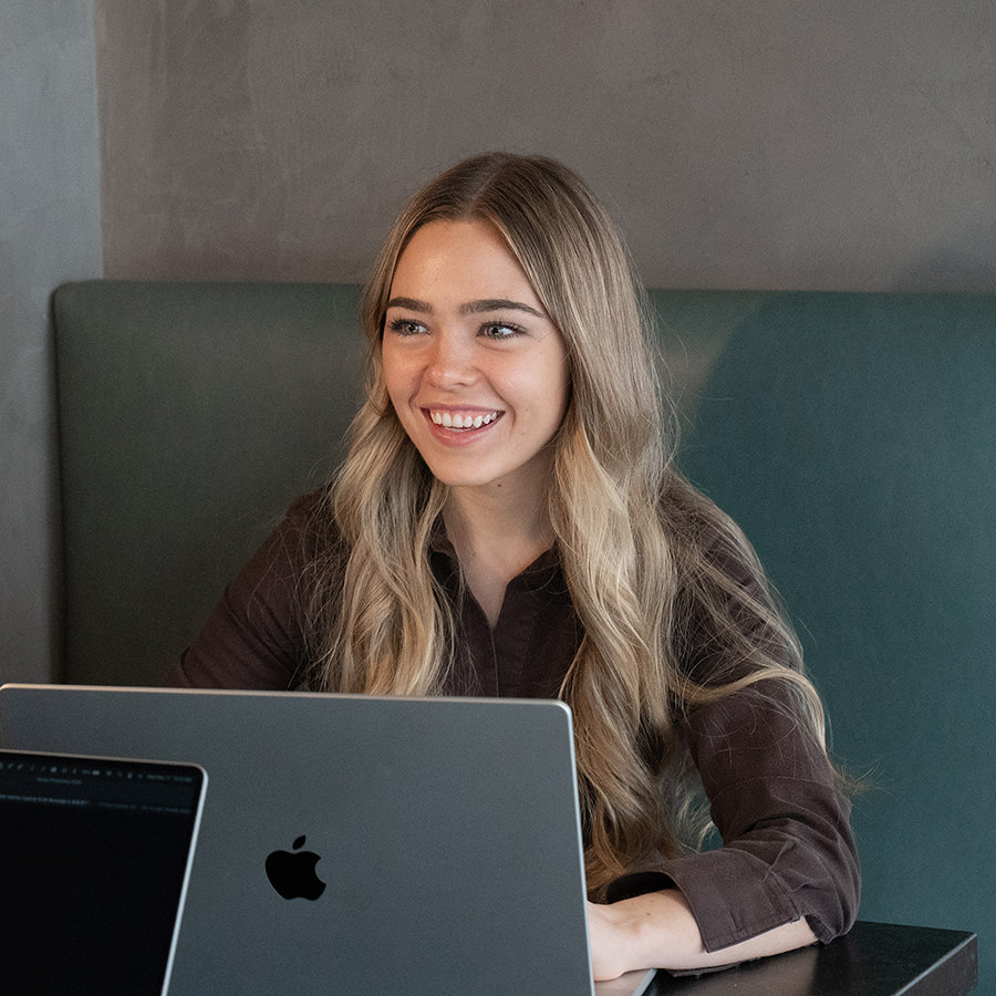 A woman smiling while working on a laptop.