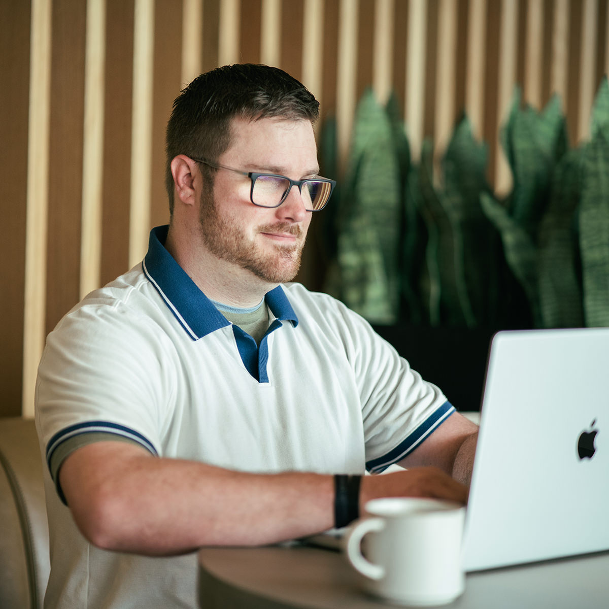 A young professional sitting at a table working on a laptop computer.