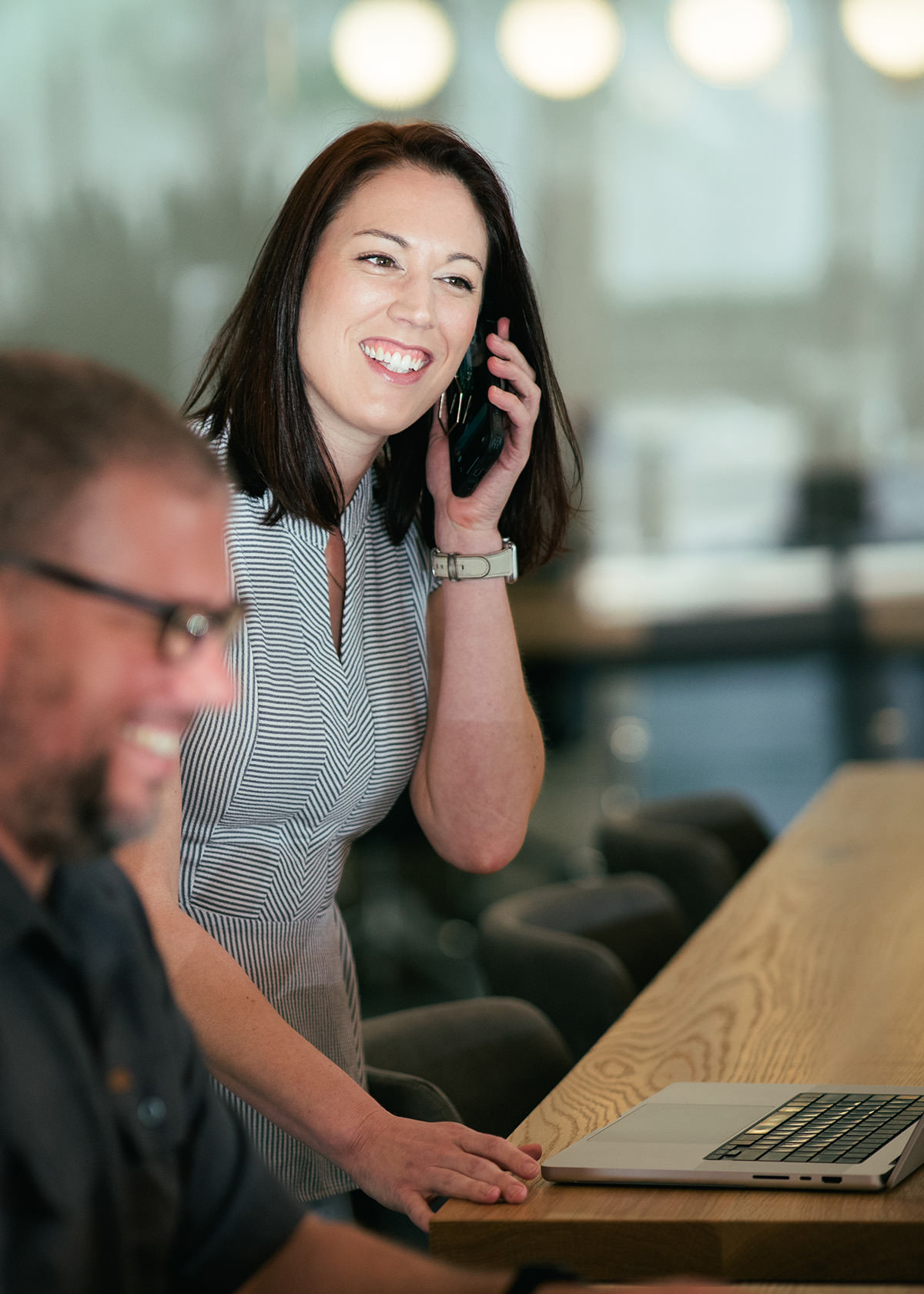 A business woman working in an open office while talking on her mobile phone.