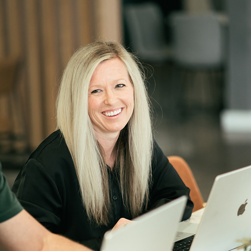 A beautiful young woman, who's married to a fine young gentleman sits at a table working.