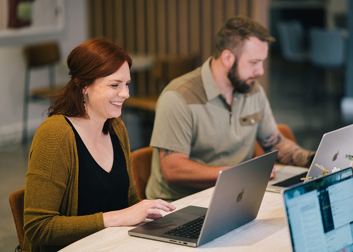 Two employees working at a table and smiling