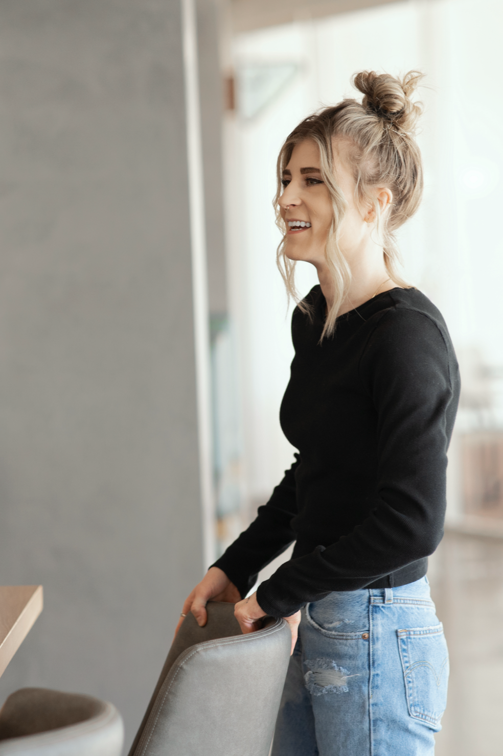 A woman standing in an open office smiling.