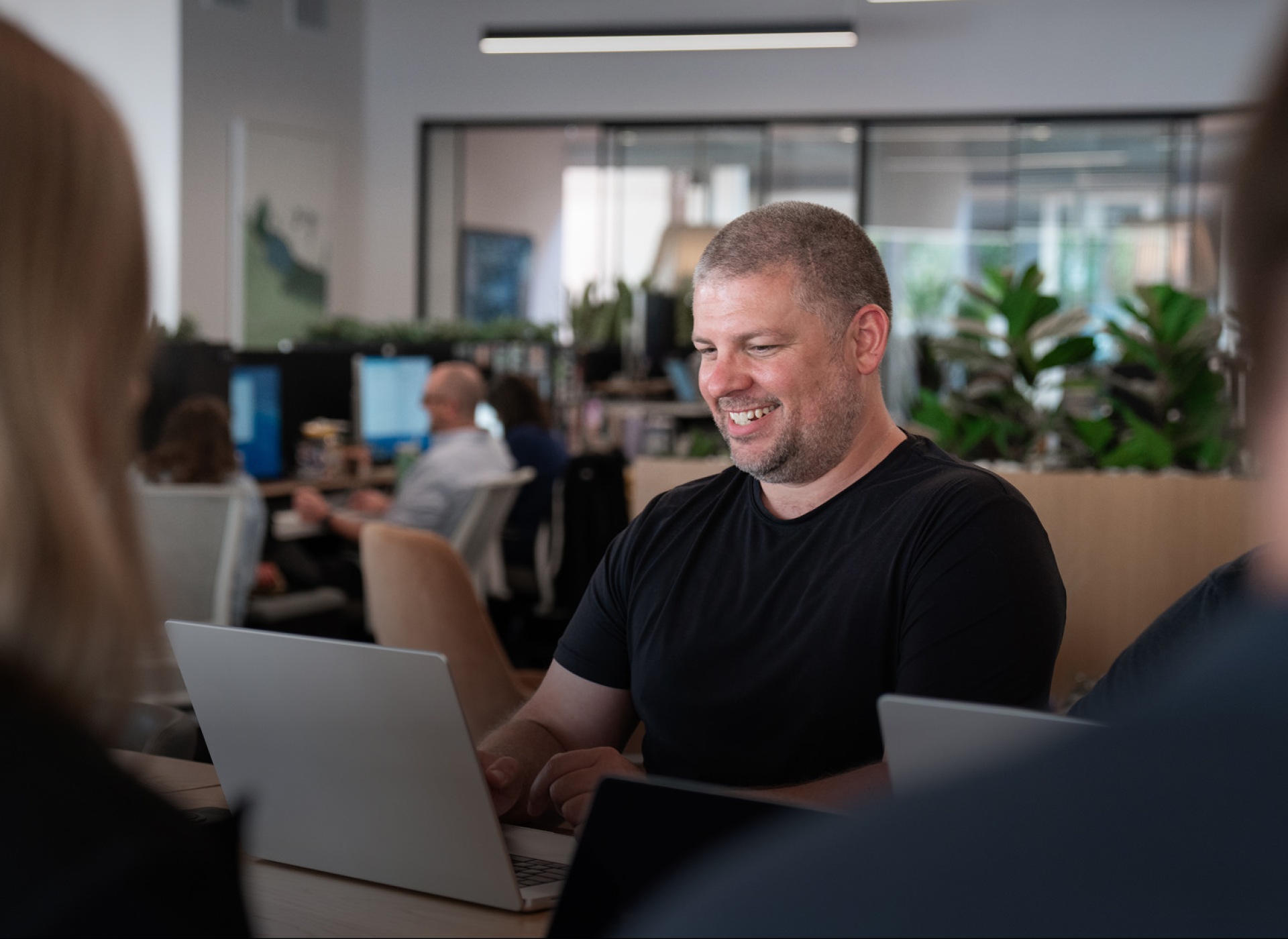 A man smiling while working on a laptop.