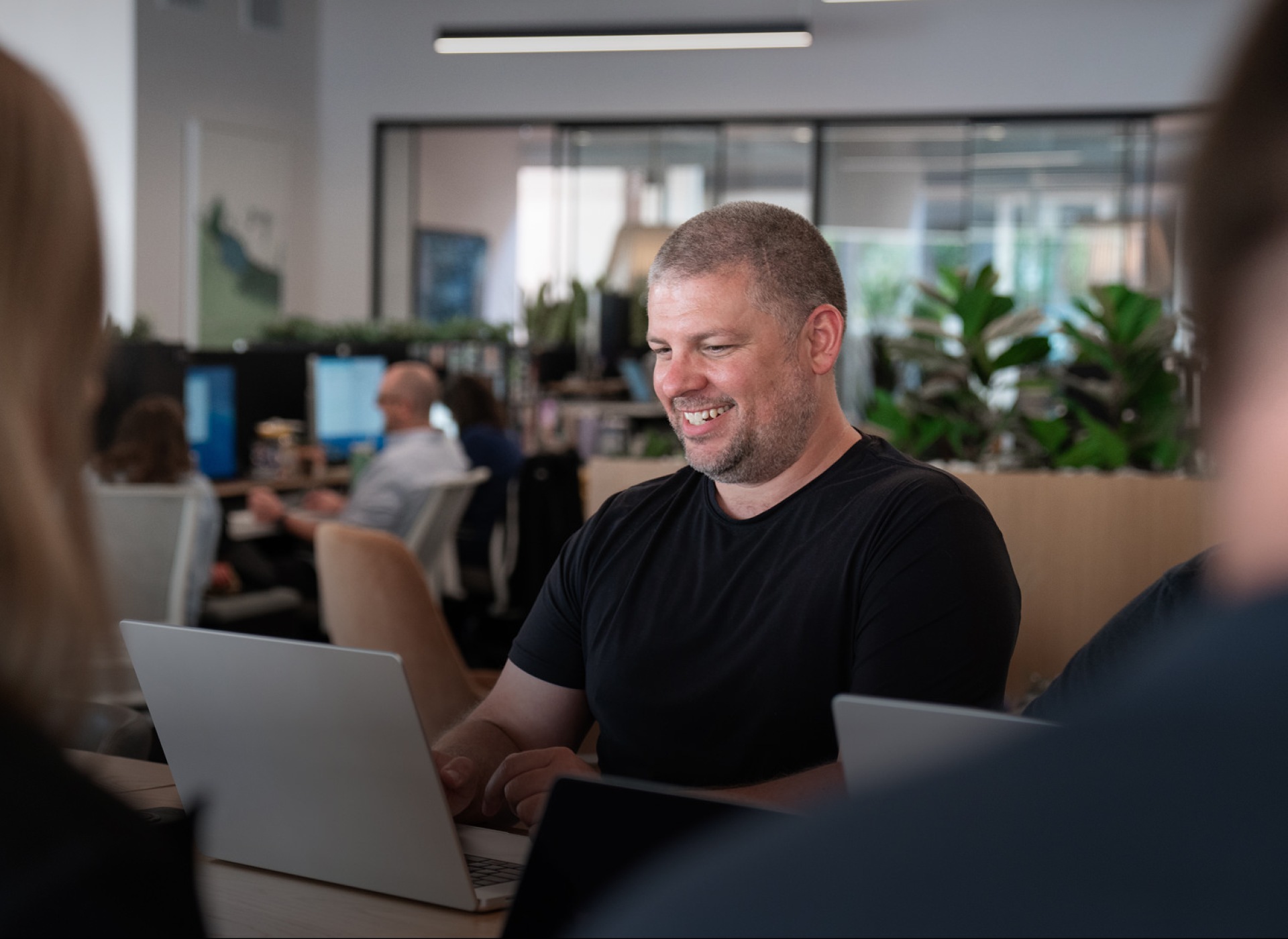 A man smiling while working on a laptop.