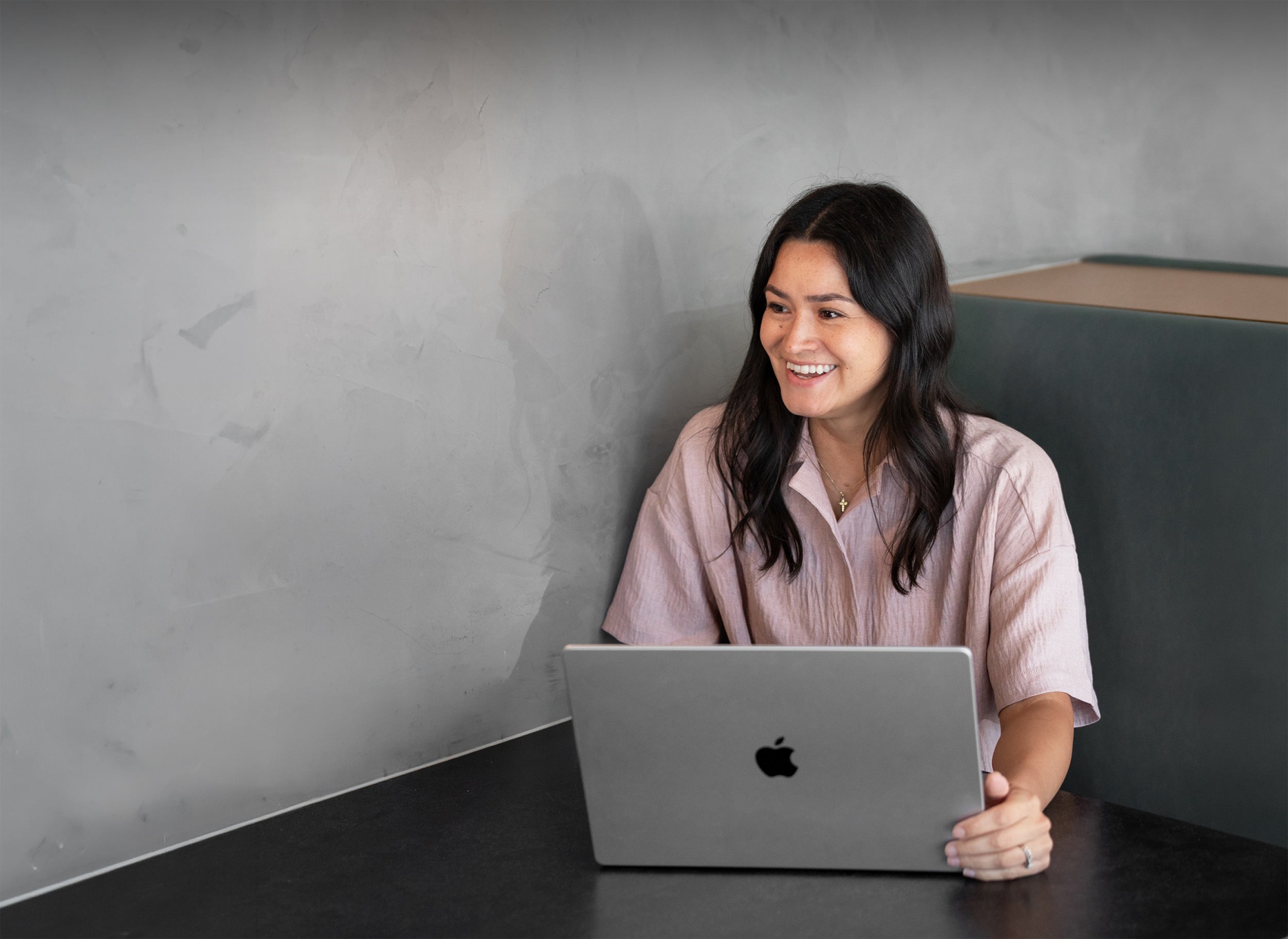 A woman smiling while working on a laptop.