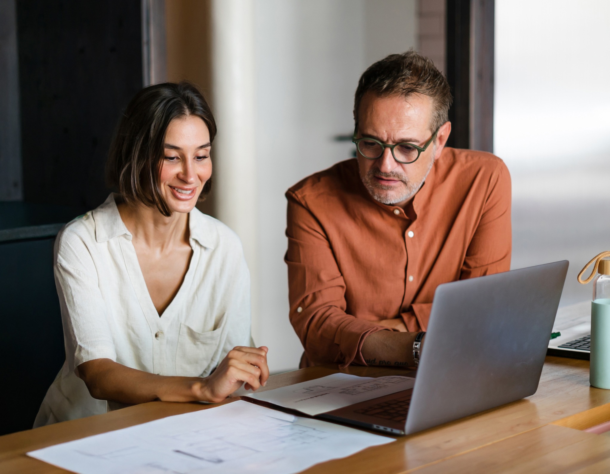 two people talking together with a laptop on desk