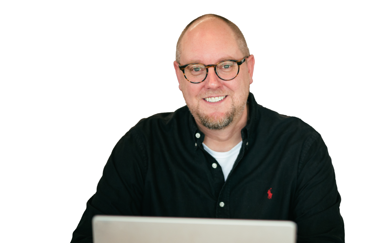 A good-looking bald man sitting with a laptop in front of him.