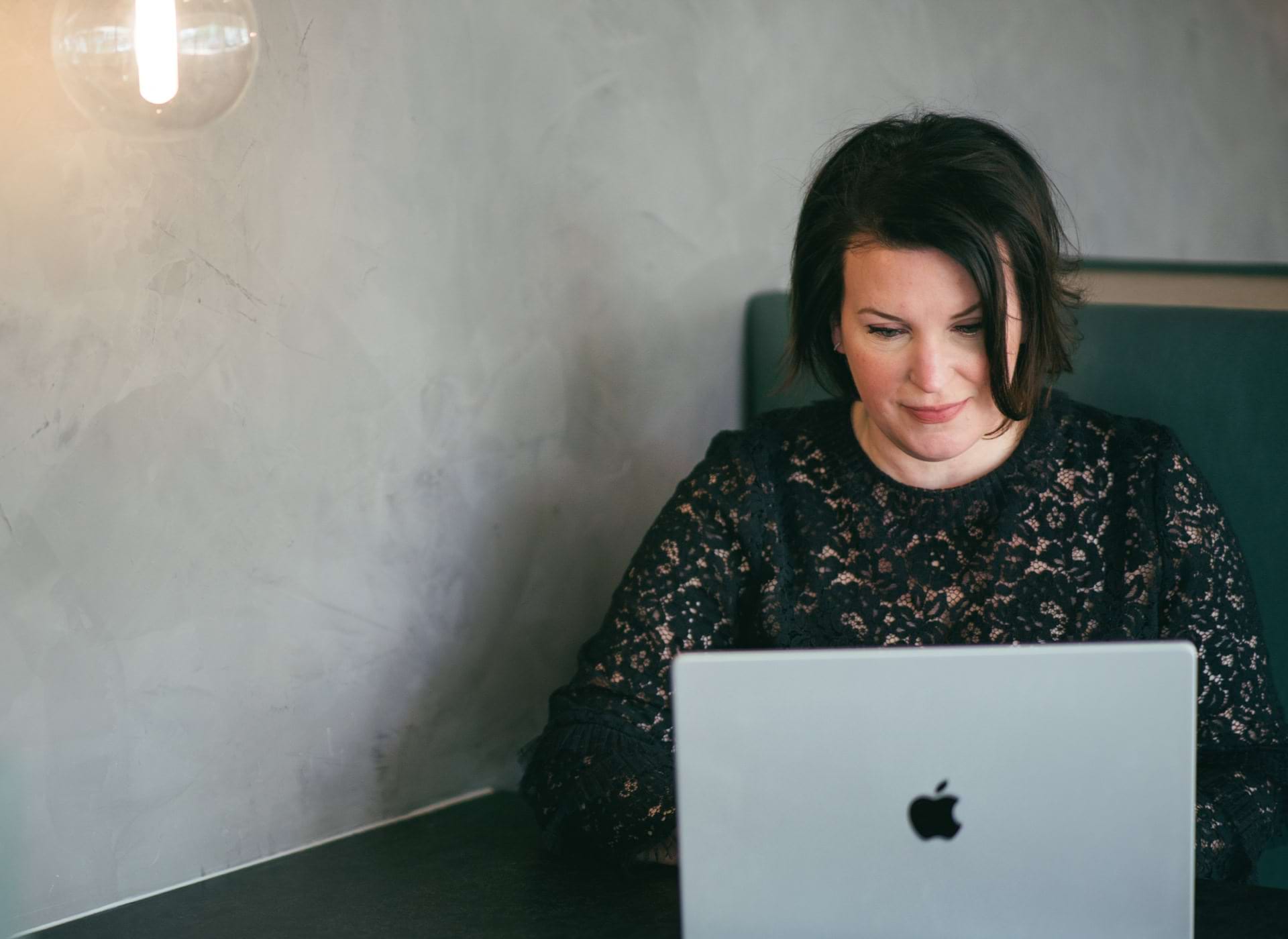 Woman sitting at a table working on a laptop computer.