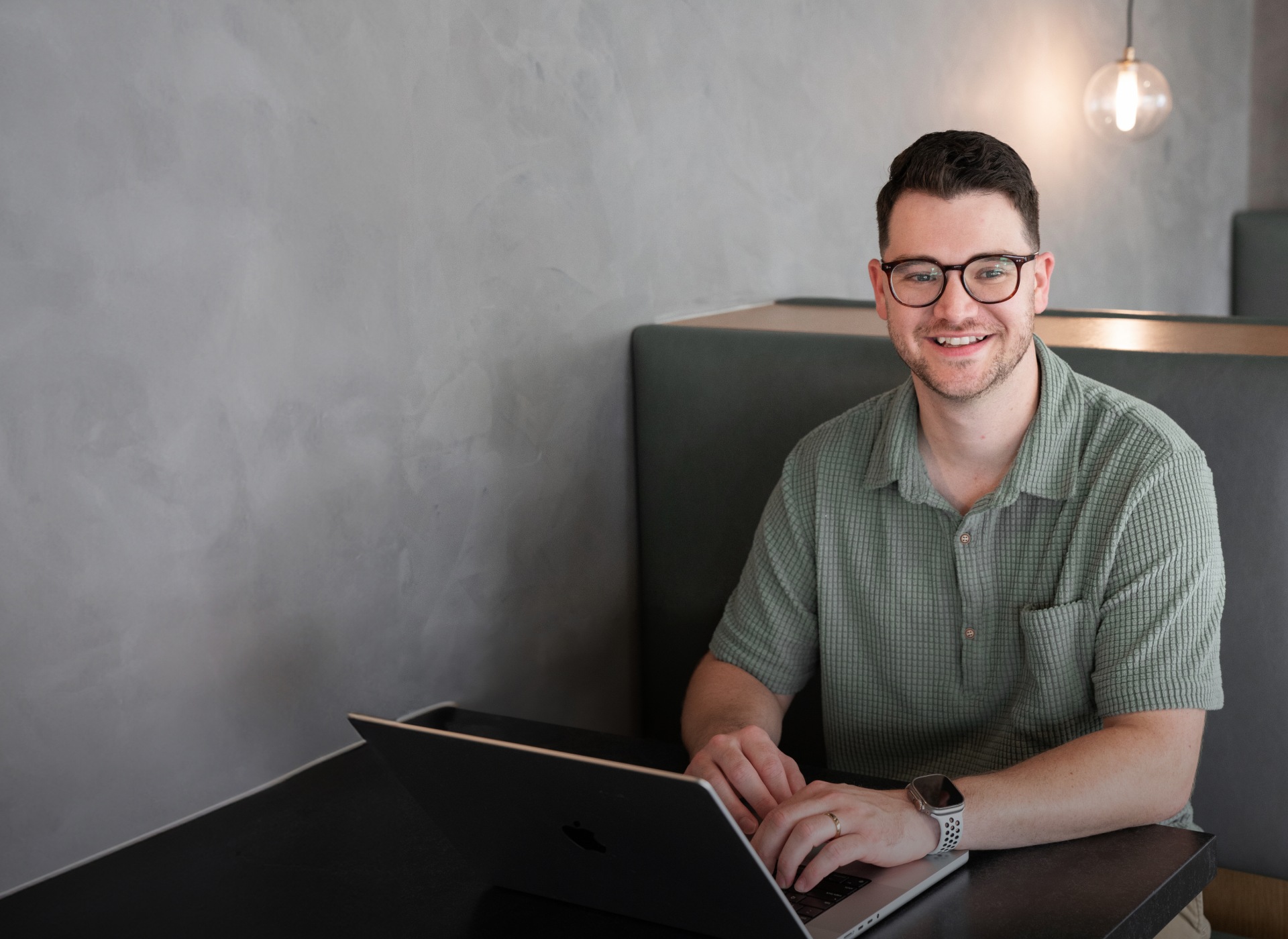 man smiling while working on his laptop