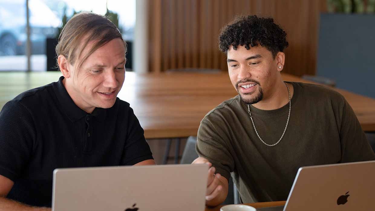 Two men working on a laptop together.
