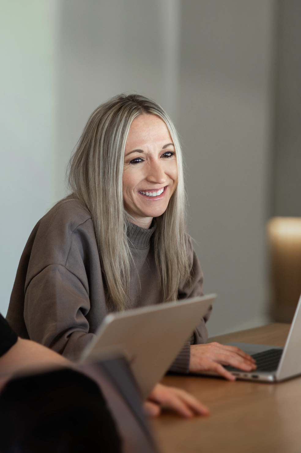 A woman working at a table looking at a laptop computer .