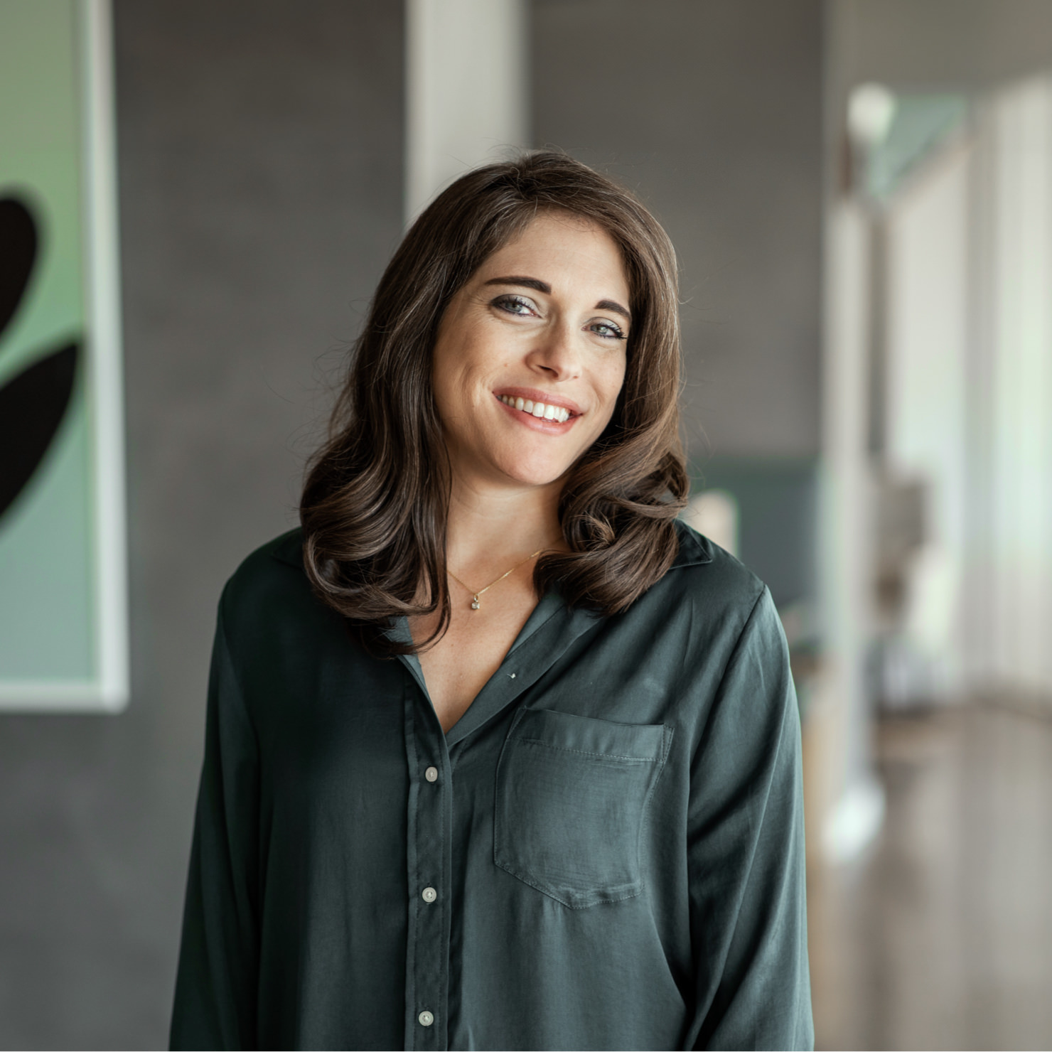 A woman standing in an open office smiling.
